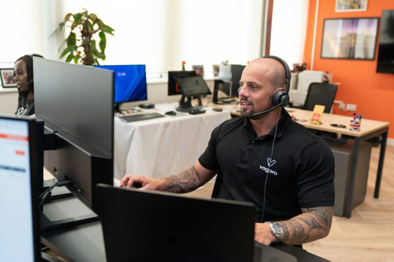 Customer support agent using a headset at a computer, illustrating phone-based identity verification risks.