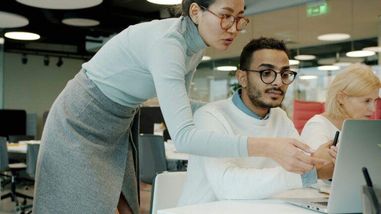 Two colleagues reviewing information on a laptop during an office planning session