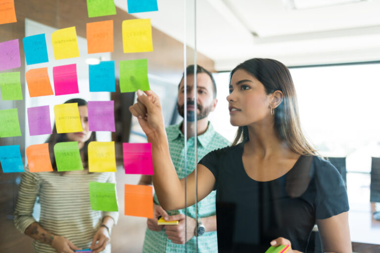 Team organising ideas and responsibilities on a glass planning board