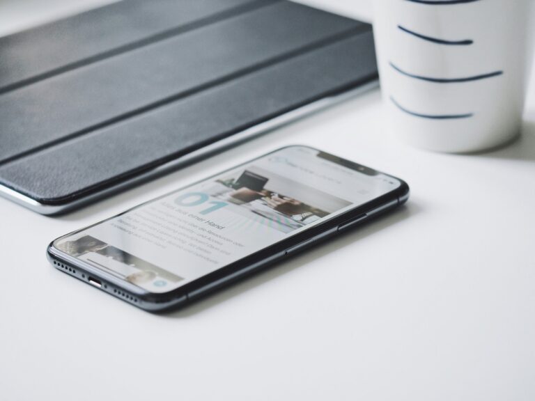Smartphone displaying a web page beside a tablet on a desk